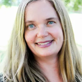 female with blonde hair and blue eyes smiling