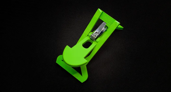 Green nail clipper holder shaped like an arrow, with nail clippers placed at the back