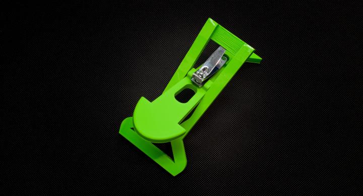 Green nail clipper holder shaped like an arrow, with nail clippers placed at the back