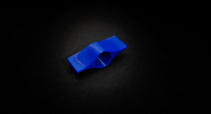 Blue toothpaste cap aid with circular opening in middle to cover top of tube. Material extensions stick out on both sides for easy twisting.